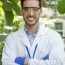 Vertical portrait of a biologist in uniform and protective gear in a greenhouse